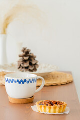 white mug in blue peas and walnut cake on a brown wooden table on a white background. Scandinavian style