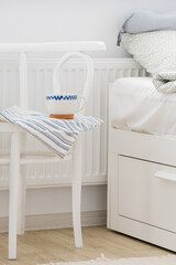 Fototapeta na wymiar Bedside table with a white mug next to the white bed. Scandinavian style. White background