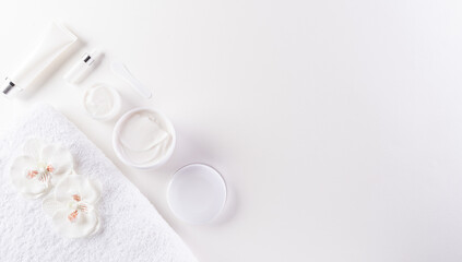 Cosmetic bottle containers, skin cream with flowers. Natural beauty and spa concept, Top view on white table background.