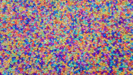 Fototapeta na wymiar Lots of different colored hydrogel balls. Set of multicolored orbis. Crystal water beads for games. Helium balloons. Can be used as a background. Polymer gel Silica gel.
