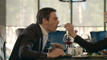 Beautiful woman feeding man at dinner. Couple in love dining in restaurant