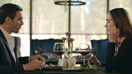 Business couple eating dinner at restaurant. Man and woman drinking wine in cafe