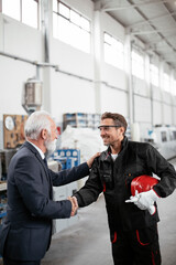 Colleagues working together. Arhitect and worker handshake in factory.
