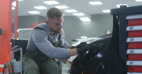 Bearded technician applying film on headlight