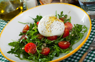 Fresh low calorie salad with Burrata cheese, cherry tomatoes and greens on plate