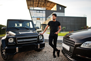 Asian man wear on all black posed near suv car.