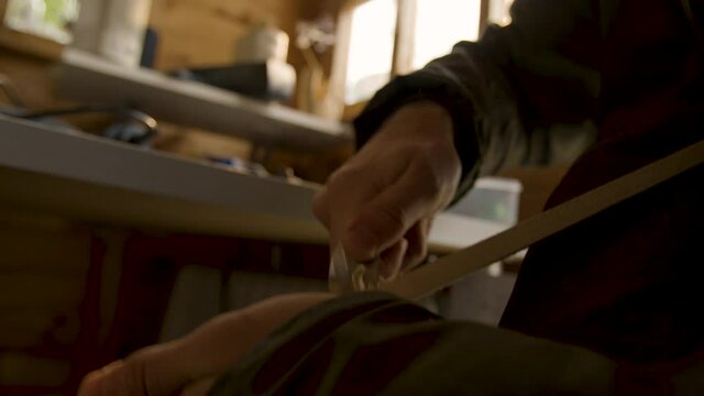 Male hand carving into a piece of wood handheld with lens flare