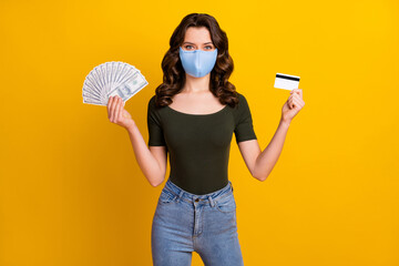 Portrait of her she attractive wavy-haired girl wear safety reusable mask holding hand bank card fan cash mers cov prevention insurance isolated bright vivid shine vibrant yellow color background