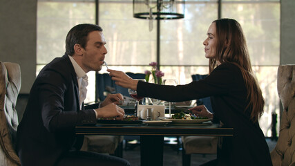 Romantic couple eating at restaurant. Man give food to woman at romantic dinner