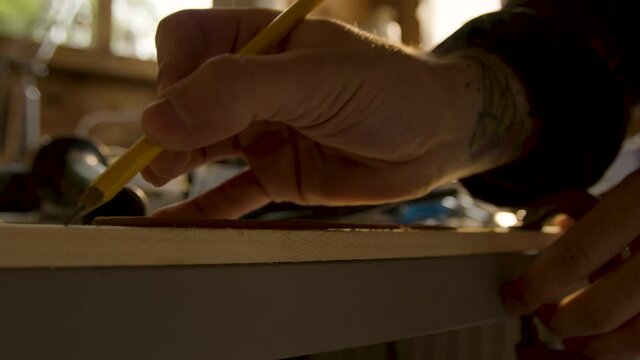 Man marking with pencil onto wood and then carving in close up