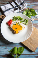 Bread toast and egg poach with ingredients on a white plate on a wooden platter