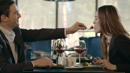 Handsome man feeding woman at romantic dinner. Couple dining at romantic date