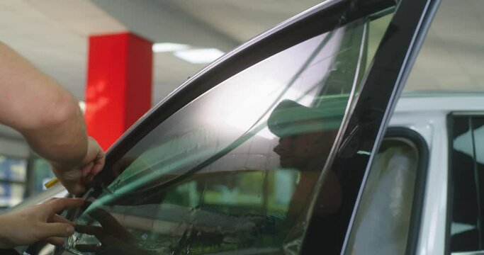 Male mechanic tinting car window