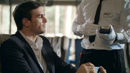 Businessman paying bill by credit card on terminal in restaurant