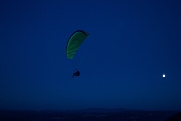 Fototapeta na wymiar Extreme paraglider flying at night, enjoy the moment. Full moon