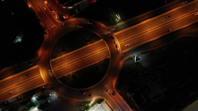Cars moving along the road, roundish highway drive, big city evening illumination. Movement in a circle. 