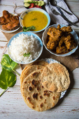 Indian chicken curry with rice, fish, lentil soup and condiments on a background