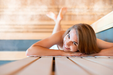 Young woman relaxing in sauna among hot steam