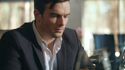 Fototapeta premium Businessman looking mobile phone at restaurant. Handsome man using cellphone