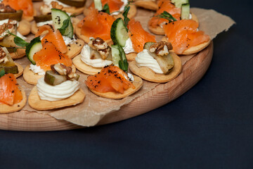Assorted snacks and canapes with salmon, walnuts, pear and fresh cucumber on a crispy gluten-free basis. Close-up, copy space