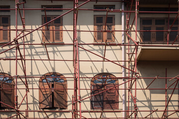 Red scaffolding structure outside of the old vintage building in construction site area during renovation project