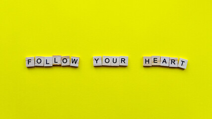 Words "Follow your heart" on a yellow paper background. Motivating web banner.