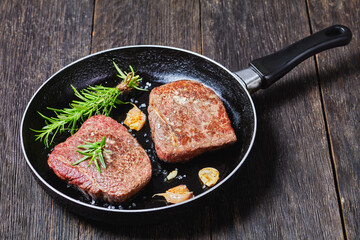 fried beef steaks on a skillet, top view