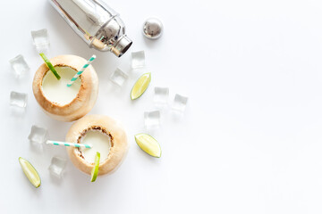 Pina Colada drink in coconut with ice cubes and shaker, top view
