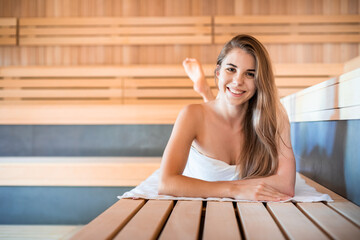 Welcome to sauna young woman relaxing and looking at camera