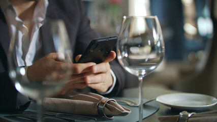 Male hands typing phone at restaurant table. Businessman using smartphone
