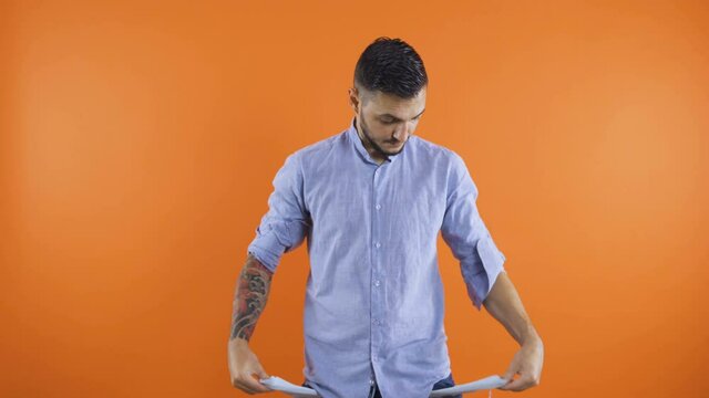 Sad young man with jeans and shirt showing empty pockets. Concept of no money. poor gestures