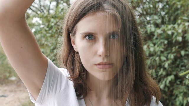 Close up portrait of Young serious female in white dress standing on the tropical beach and throwing white sand. Image of wasted time. Charming attractive Appearance