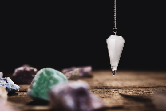Fortunetelling and horoscope with a pendulum and healing gemstones, black background