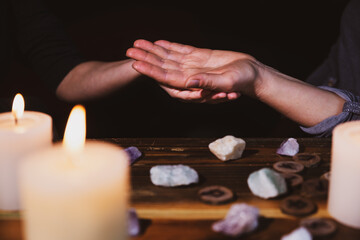 palmistry or palm reading, fortuneteller holding a hand, healing stones and candles