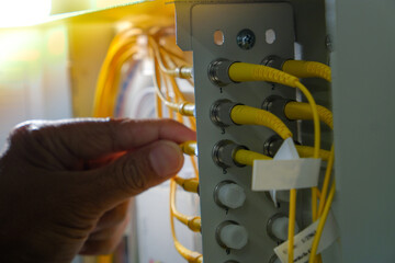 Hand of system engineer and fiber optic cable connected to enclosure box in a technology data...