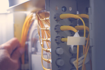 Hand of system engineer and fiber optic cable connected to enclosure box in a technology data...