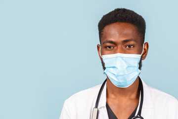 African American male doctor with stethoscope in mask over blue background.