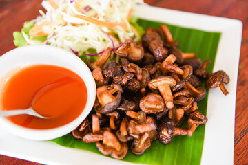 Delicious fried mushrooms in plate on wooden table, top view - cooked shiitake mushrooms fried with tomato sauce and vegetables