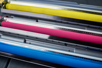 Magenta, cyan and yellow toner cartridges for color laser printers stacked on gray wooden background