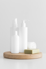 Set of white cosmetic bottles mockup with a natural soap and a towel on a white table.