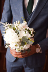 bride and groom with bouquet
a man in a suit holds in his hand a bouquet of the bride
