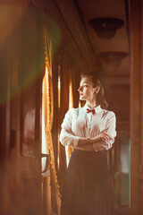 young woman in vintage clothes looking out the window inside a retro train