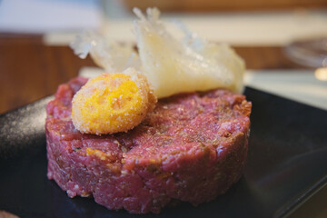 Delicious raw meat tartar with egg yolk, sun-dried tomatoes, spices and parmesan cheese