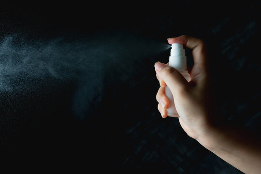 Close Up Woman Handing Small Spray Bottle And Spraying On Dark Background