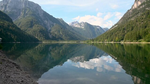 View of Lake Lago del Predil in Italy near Slovenian border. Pristine Alpine lake in late summer. Alps mountains surrounding clean and natural pond. Right pan, handheld, 4K