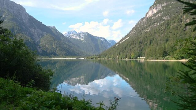 View of Lake Lago del Predil in Italy near Slovenian border. Pristine Alpine lake in late summer. Alps mountains surrounding clean and natural pond. Static, handheld, 4K