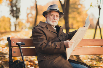 Photo of serious old man grumpy pensioner dont like kids play autumn town park sit bench read look...