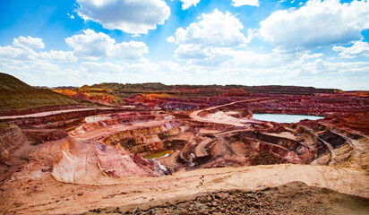 Aluminium ore (bauxite clay) mining in quarry. Mining machines and heaps of color empty stones on...