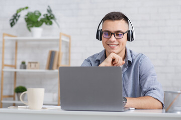 Student or employee at home during quarantine covid-19. Cheerful guy watches online lesson in laptop