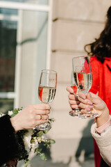 Hands of people, bride, groom and guests are holding the glasses